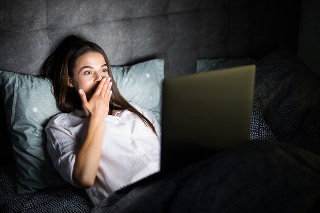 Jonge vrouw in bed met laptop in de nacht