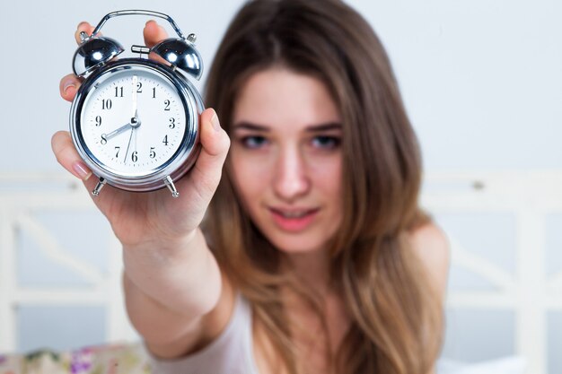 Jonge vrouw in bed met wekker