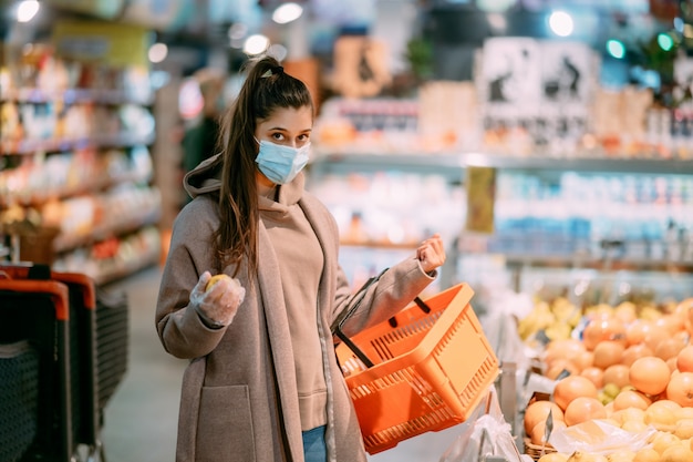 Jonge vrouw in beschermend masker maakt aankopen