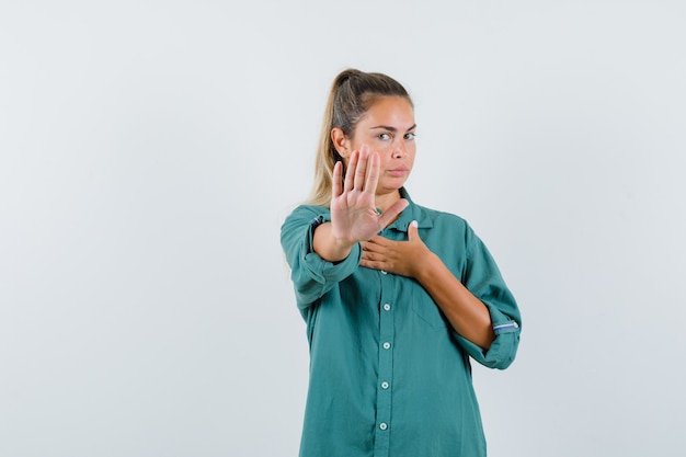 Jonge vrouw in blauw overhemd die afwijzingsgebaar tonen en ernstig kijken