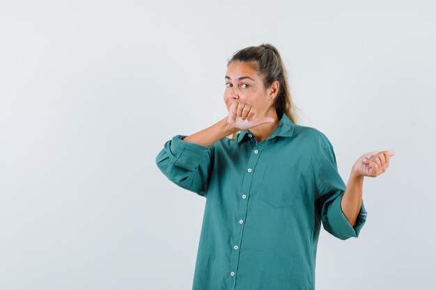 Jonge vrouw in blauw shirt die terug wijst en aandachtig kijkt