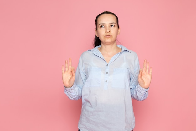 jonge vrouw in blauw shirt poseren op de roze muur