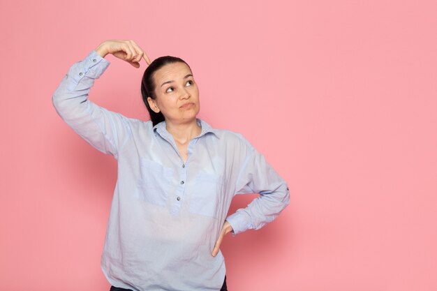 jonge vrouw in blauw shirt poseren op de roze muur