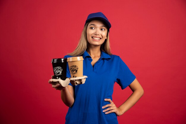 Jonge vrouw in blauw uniform met een doos van twee kopjes.