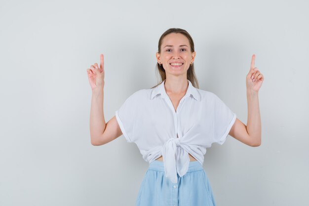 Jonge vrouw in blouse, rok die omhoog wijst en gelukkig kijkt