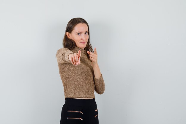 Jonge vrouw in blouse, rok wijzend op camera en op zoek zelfverzekerd, vooraanzicht. ruimte voor tekst