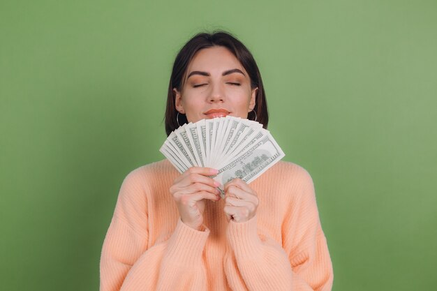 Jonge vrouw in casual perziksweater die op groene olijfmuur wordt geïsoleerd