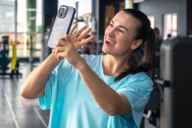 Gratis foto jonge vrouw in de sportschool met een smartphone neemt een selfie