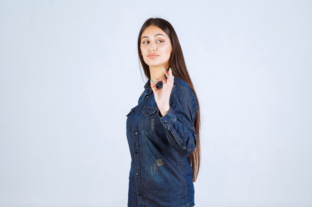 Jonge vrouw in denimoverhemd die plezierteken tonen