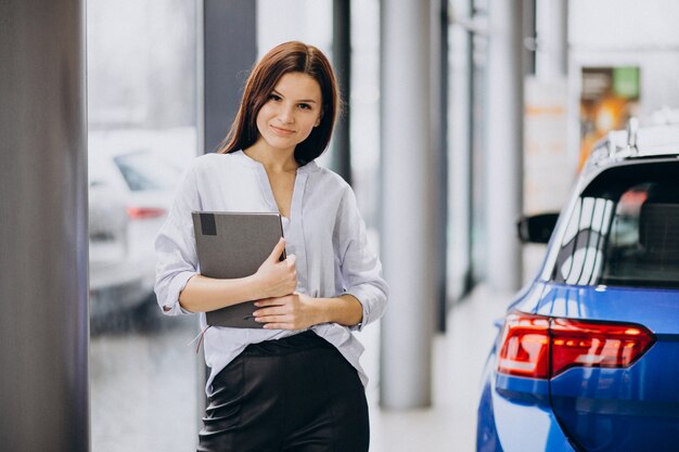 Jonge vrouw in een autotoonzaal die een auto kiest