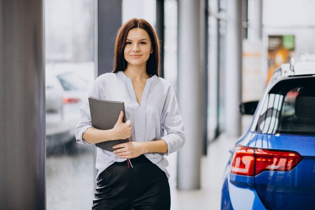 Jonge vrouw in een autotoonzaal die een auto kiest