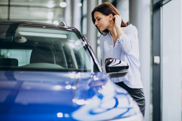 Jonge vrouw in een autotoonzaal die een auto kiest