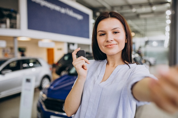 Jonge vrouw in een autotoonzaal die een auto kiest