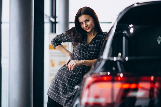 Jonge vrouw in een autotoonzaal die een auto kiest