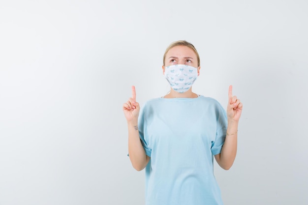 Jonge vrouw in een blauw t-shirt met een medisch masker