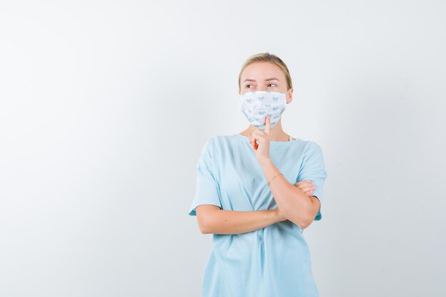 Jonge vrouw in een blauw t-shirt met een medisch masker