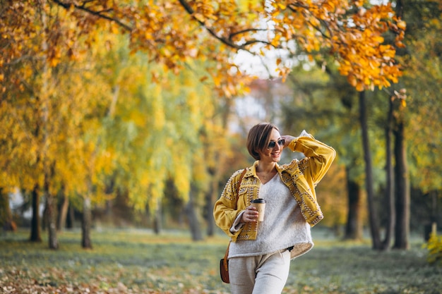 Jonge vrouw in een herfst park koffie drinken