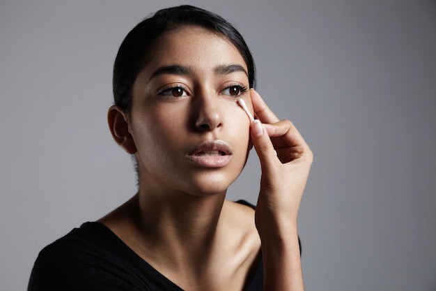 Jonge vrouw in een profielportret die een make-up corrigeert
