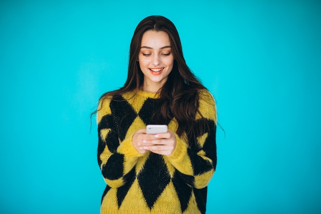 Jonge vrouw in een warme trui met behulp van de telefoon