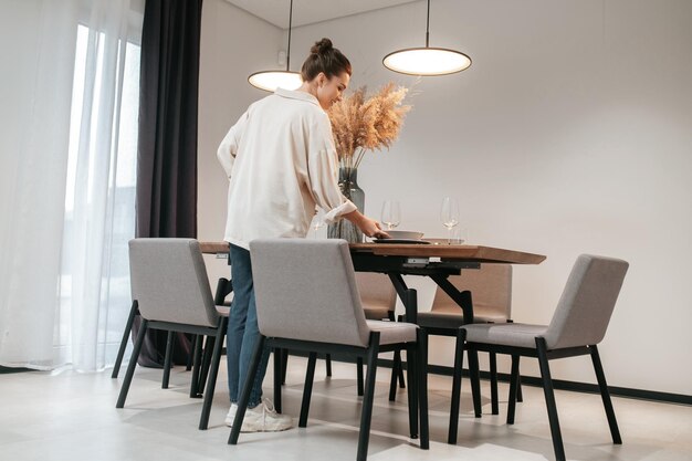 Jonge vrouw in een wit overhemd die borden op tafel zet