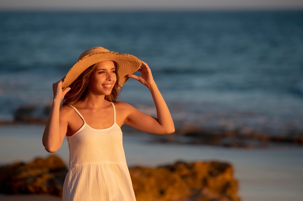 Jonge vrouw in een witte jurk aan zee