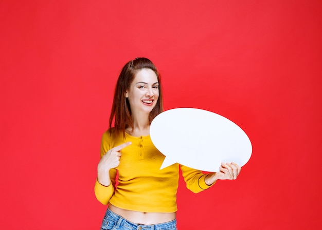 Jonge vrouw in geel shirt met een ovale infobord