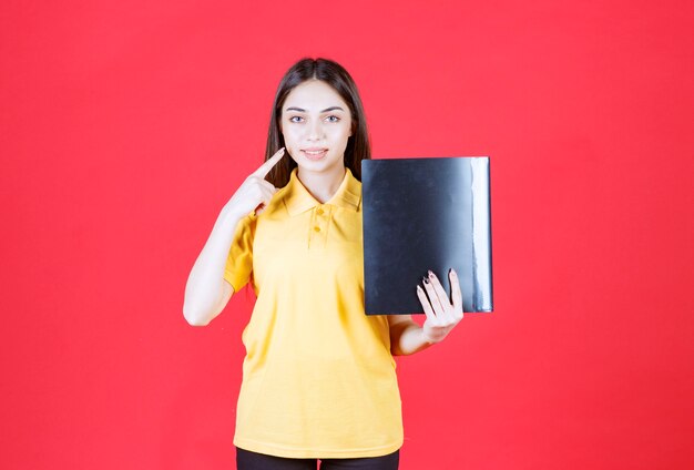 Jonge vrouw in geel shirt met een zwarte map