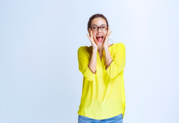 Jonge vrouw in geel shirt voelt zich positief en lacht