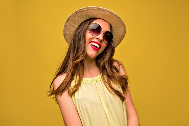 Jonge vrouw in gele jurk met hoed en zonnebril