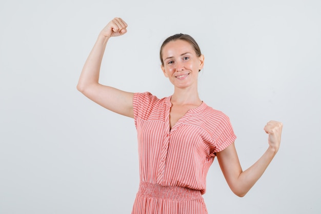 Gratis foto jonge vrouw in gestreepte kleding die winnaargebaar toont en gelukkig, vooraanzicht kijkt.