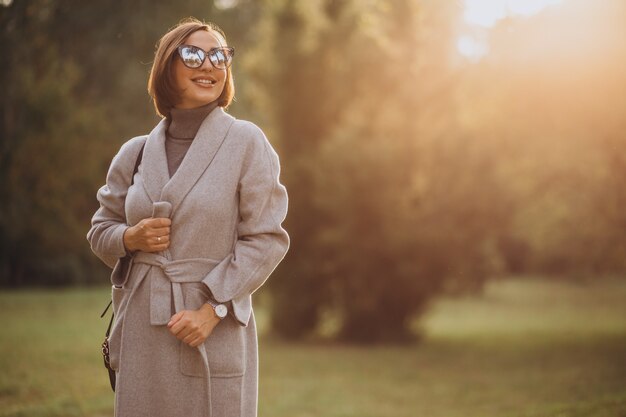 Jonge vrouw in grijze jas wandelen in een herfst park