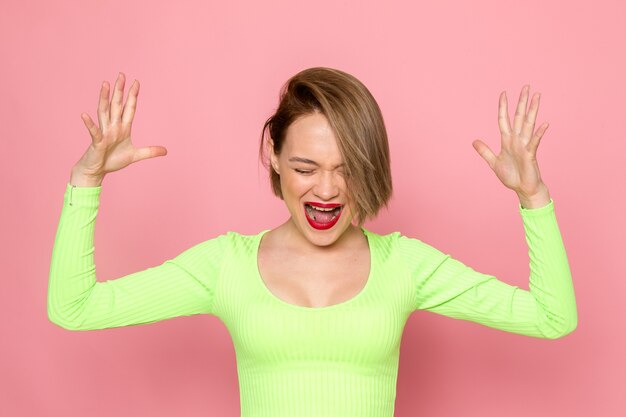 jonge vrouw in groen shirt en grijze broek poseren met emotionele uitbarsting