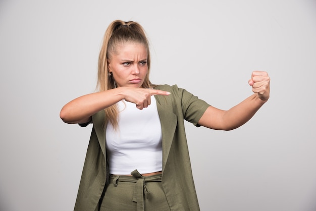 Jonge vrouw in groene jas wijzend op iets.