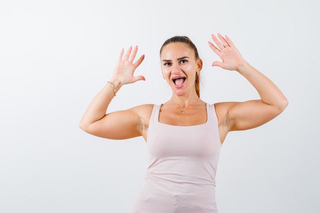 Jonge vrouw in hemd met palmen in overgave gebaar en op zoek energiek, vooraanzicht.