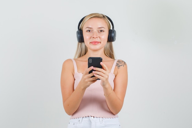 Jonge vrouw in hemd, minirok, koptelefoon met smartphone