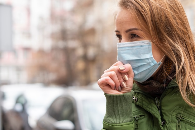 Jonge vrouw in het beschermende steriele medische masker hoesten