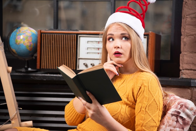 Jonge vrouw in kerstmuts lezen van een boek.