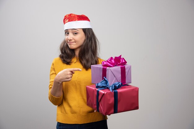 Jonge vrouw in kerstmuts met kerstcadeautjes.