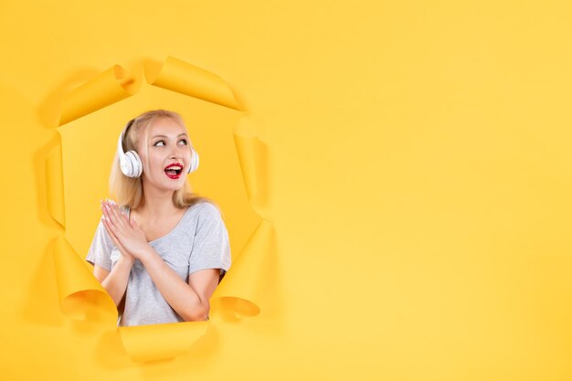 Jonge vrouw in koptelefoon op gescheurd geel papier achtergrond audio echografie klinkt muziek