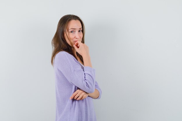 Jonge vrouw in lila blouse poseren terwijl opzij kijken en schattig kijken