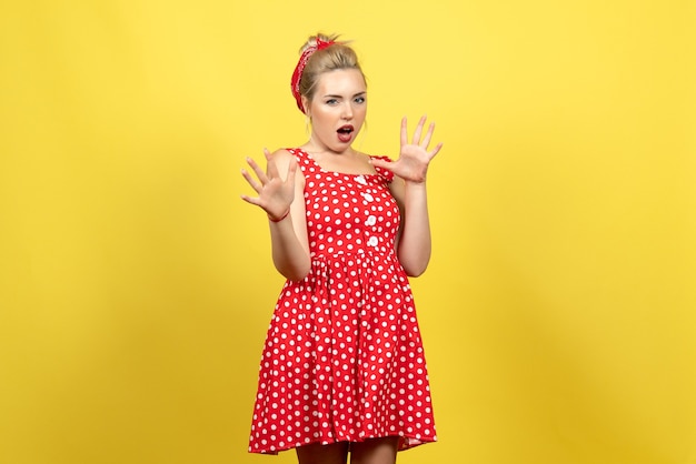 jonge vrouw in rode polka dot jurk gewoon staande op geel