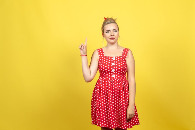 jonge vrouw in rode polka dot jurk haar vinger op geel