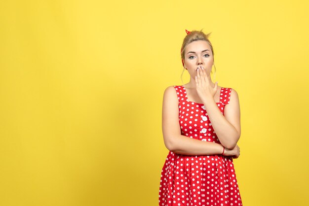 jonge vrouw in rode polka dot jurk poseren op geel