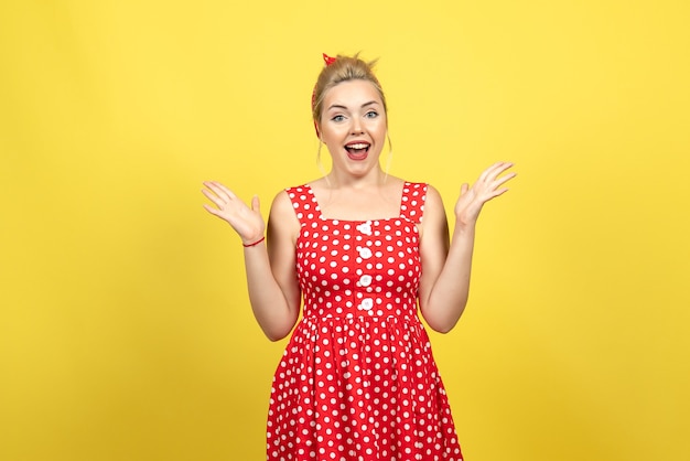 jonge vrouw in rode polka dot jurk poseren op geel