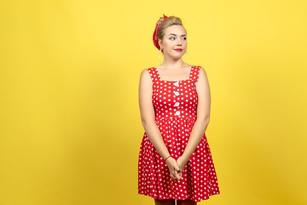 jonge vrouw in rode polka dot jurk poseren op geel