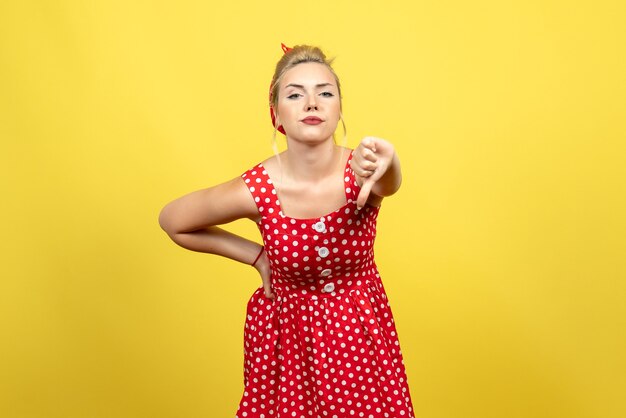 jonge vrouw in rode polka dot jurk weergegeven in tegenstelling tot teken op geel