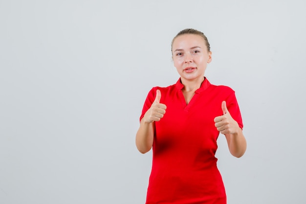 Jonge vrouw in rode t-shirt duimen opdagen en tevreden kijken