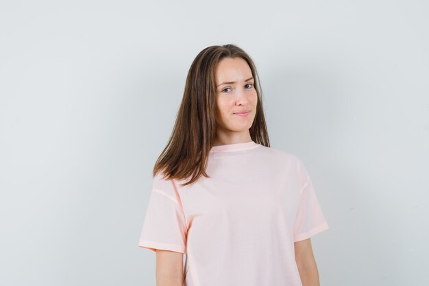 Jonge vrouw in roze t-shirt en op zoek verstandig, vooraanzicht.