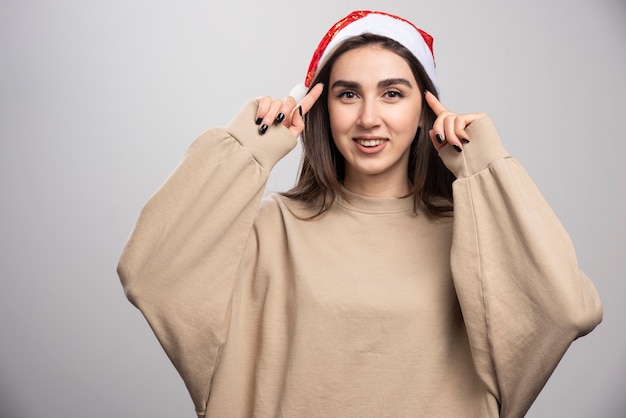 Jonge vrouw in Santa's hoed poseren studio-opname geïsoleerd op grijs.