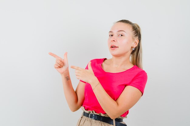 Jonge vrouw in t-shirt en broek die naar de kant wijst en zelfverzekerd kijkt